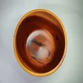 Cuenco de madera de caoba visto desde arriba, forma redondeada y vetas oscuras visibles sobre fondo blanco