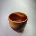 Cuenco artesanal de madera de caoba con forma redondeada, visto desde un ángulo elevado sobre fondo blanco